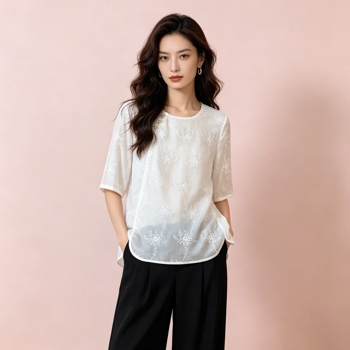 Semi sheer white embroidered shirt worn untucked over black trousers