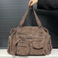 Mocha brown PU shoulder bag held up by its twin handles, front pockets and end zip pockets in view