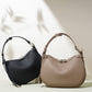 Black and taupe pebbled leather crescent bags with silver tone ring hardware side by side