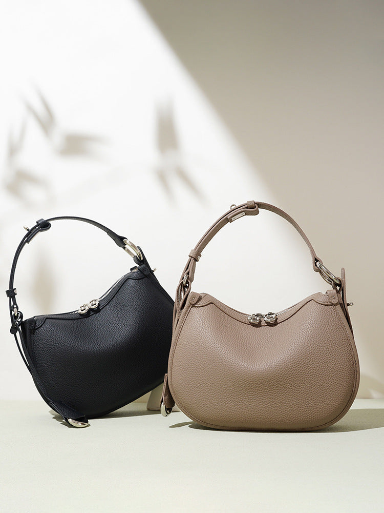 Black and taupe pebbled leather crescent bags with silver tone ring hardware side by side
