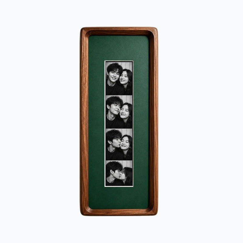 Black walnut photo strip frame with dark green lining holding four black and white photos on a plain background