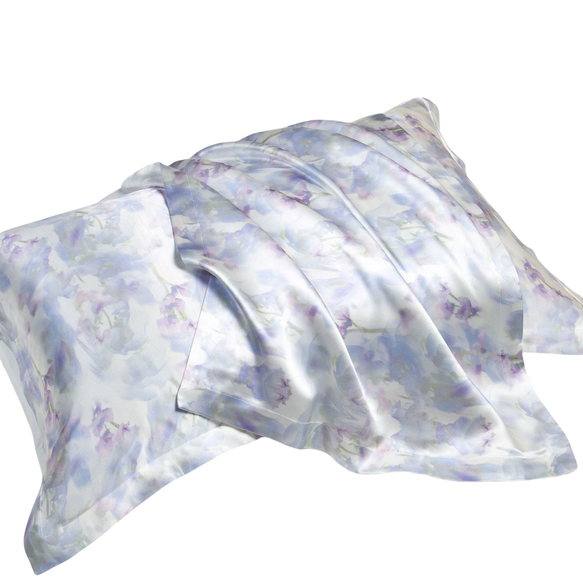Two lilac and white watercolor print silk pillowcases on a white background, one folded over the other