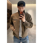 Man in a brown washed cotton jacket with a chest zip pocket, taking a mirror photo in a room with wooden shelves