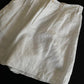 Angled view of white linen shorts showing the loose wide-leg cut and slub texture