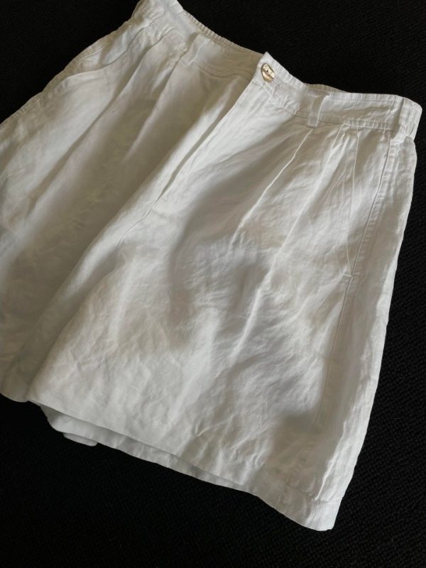 Angled view of white linen shorts showing the loose wide-leg cut and slub texture