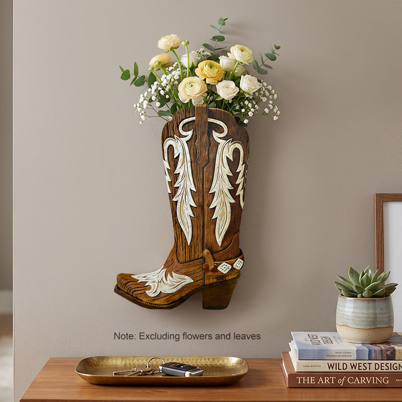 Brown wooden cowboy boot wall vase with cream scroll inlay, holding flowers by a console