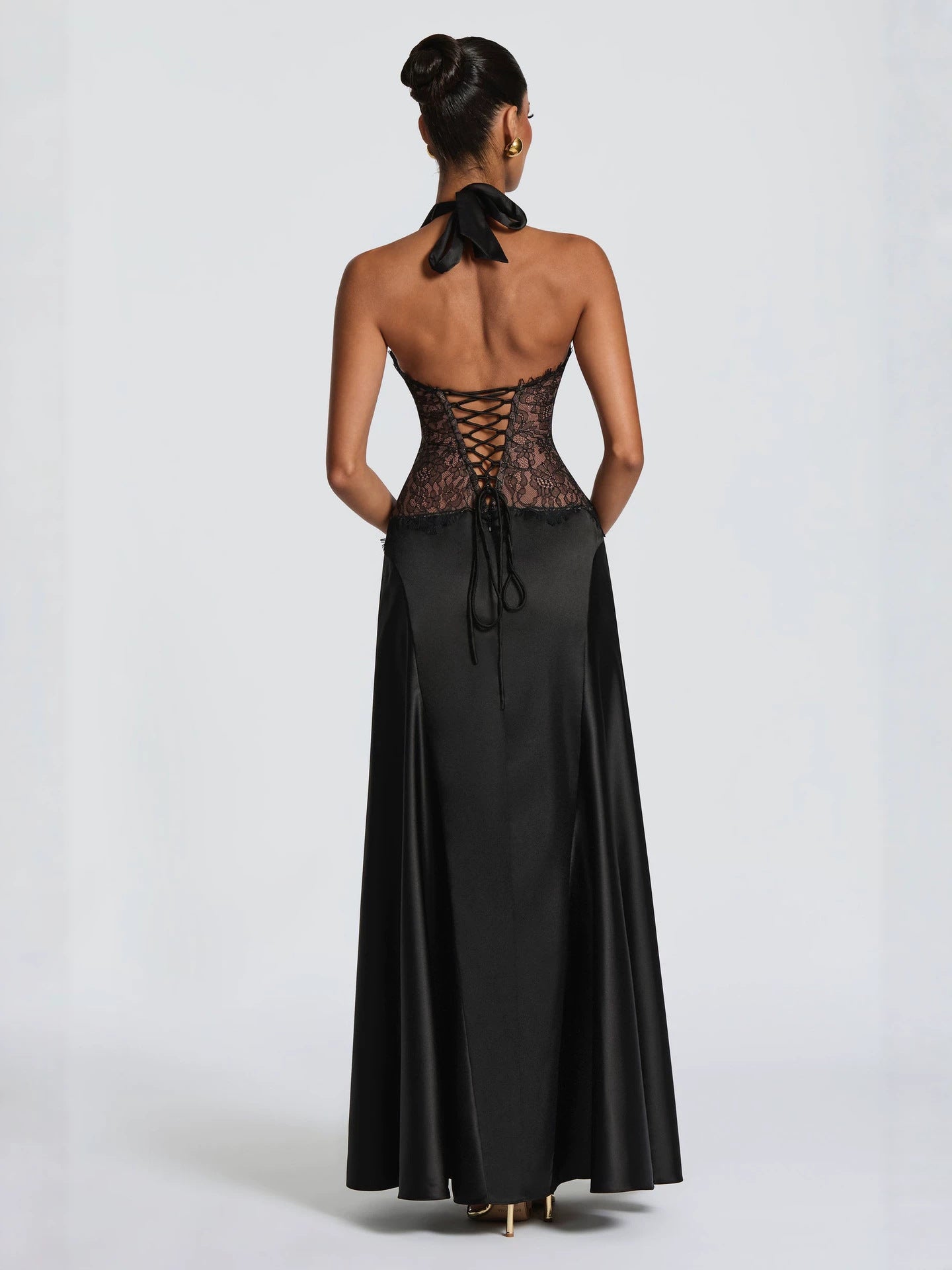 Back of the black gown showing the open back and lace up corset tie at the waist