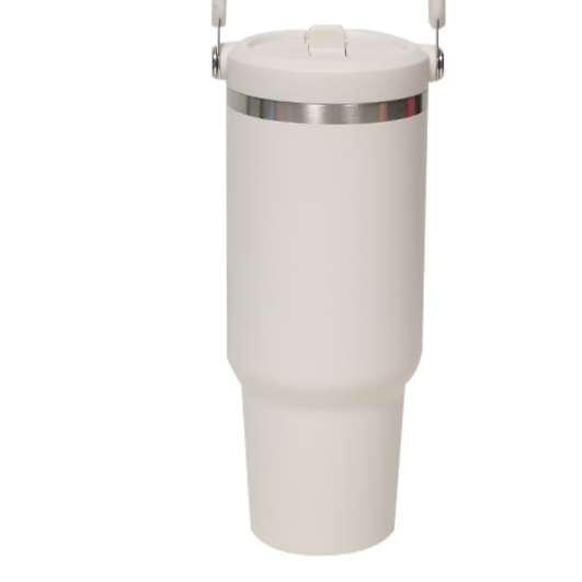 Cream insulated tumbler with a stainless steel ring below the flip lid and a handle at the top