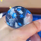 Close view of a clear blue gel cube squishy with white snowflakes suspended in the gel
