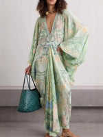 Woman in a light green floral V-neck dress with wide sleeves holding a teal woven tote bag