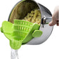 Green silicone clip-on pot strainer on a stainless steel pot draining pasta, water pouring from the spout