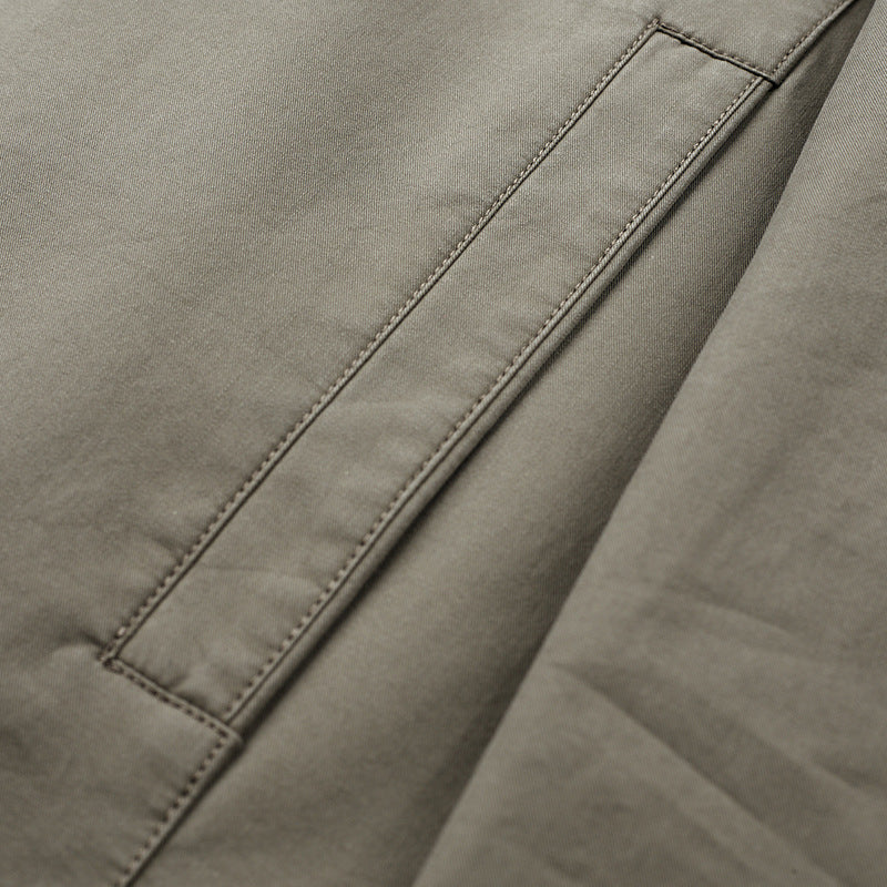 Close view of a slanted side pocket with edge stitching on the khaki cotton fabric of the jacket
