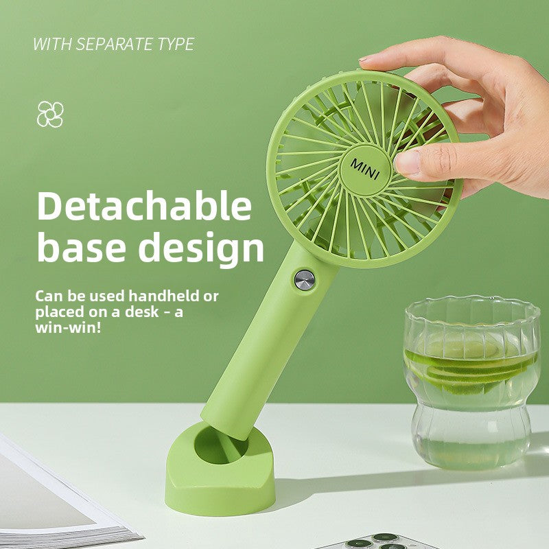 Handheld USB fan held in one hand pushing a breeze on a warm day