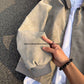 Close-up of the rib knit cuff and sleeve of the beige tie-dye PU leather jacket held in one hand