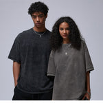 Man in a washed black t-shirt and woman in a washed gray t-shirt, both loose with dropped shoulders