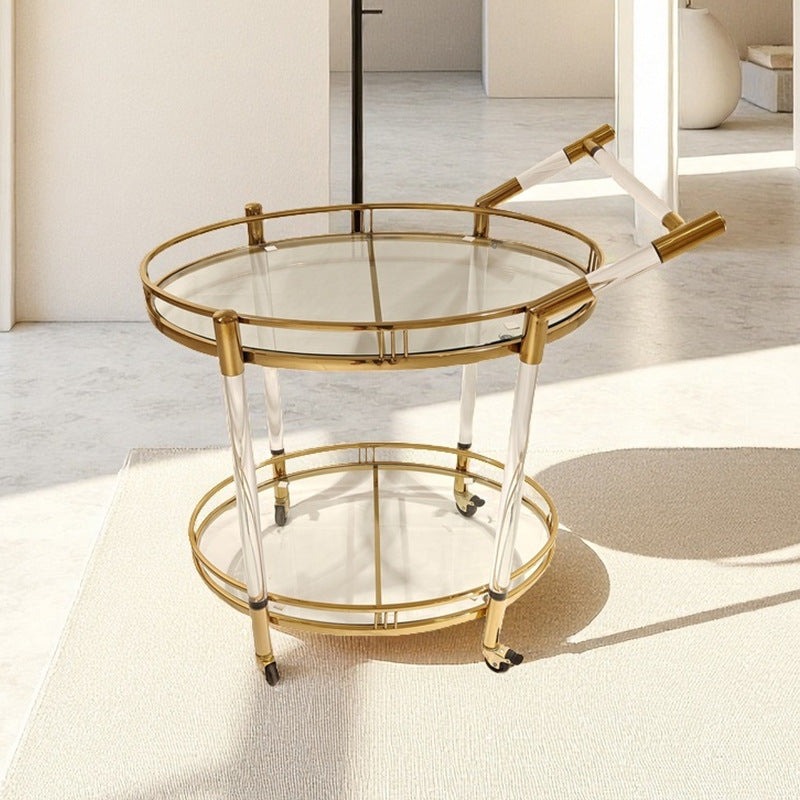 Close view of the gold stainless steel frame and clear acrylic legs of the serving cart