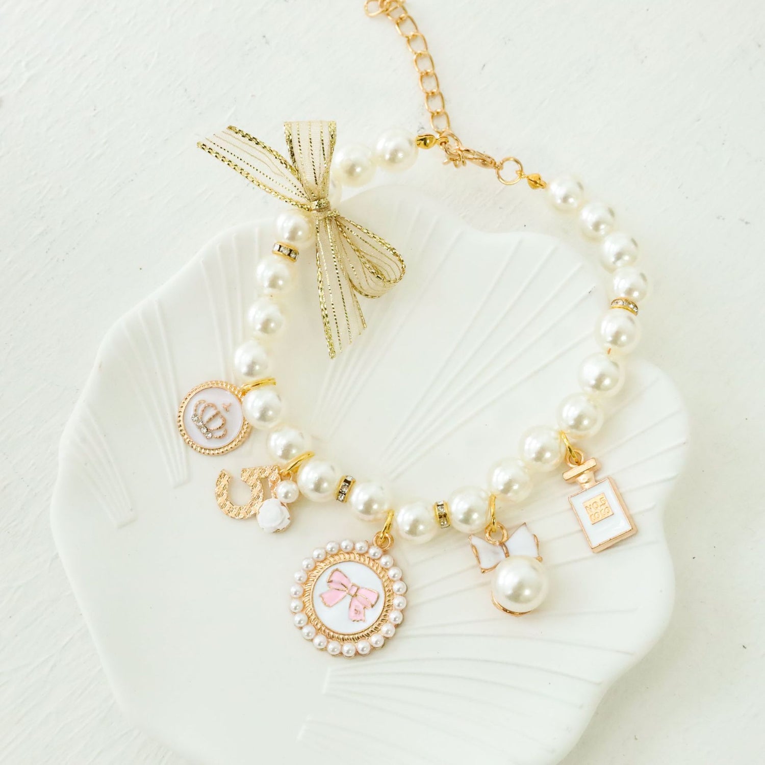 Close view of faux pearl pet collar charms including a bow cameo, crown medallion and rose