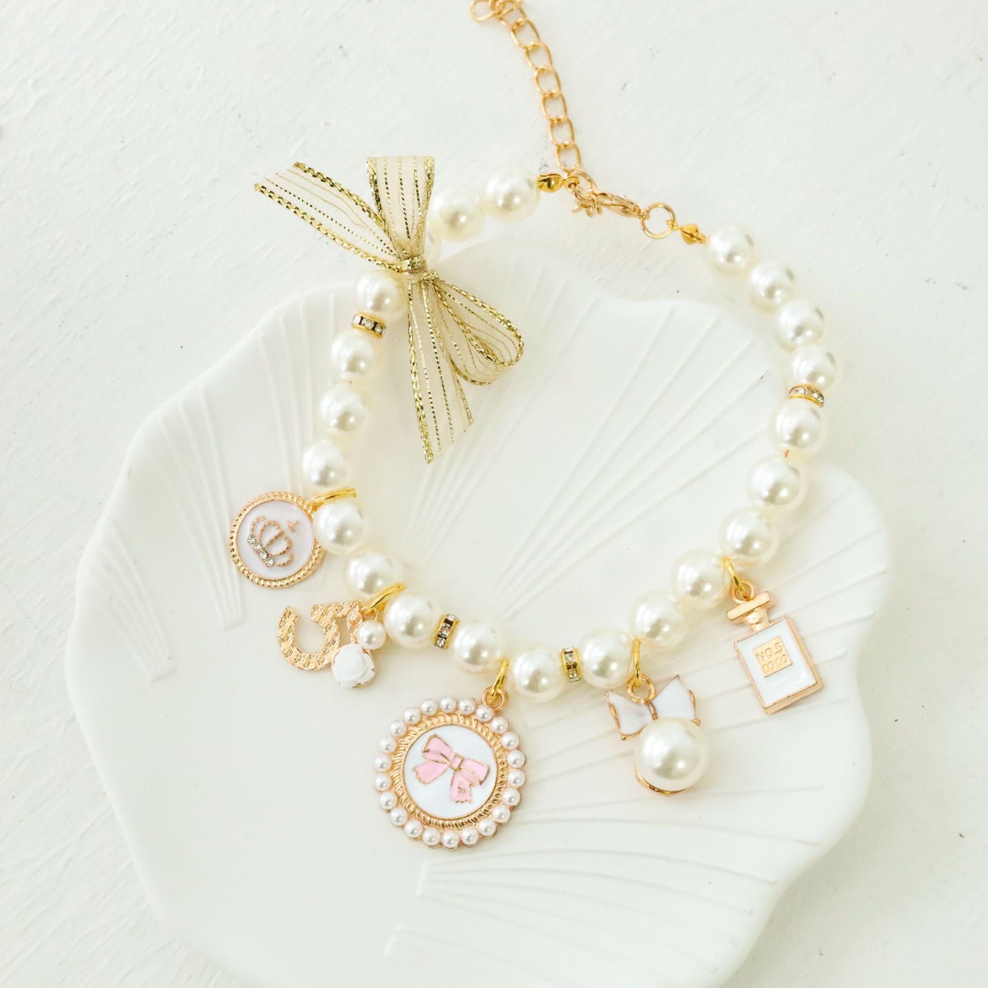 Close view of faux pearl pet collar charms including a bow cameo, crown medallion and rose