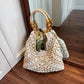 Off-white open-weave hobo bag with a light cord and wooden bead handle, daisies tucked inside, by a door