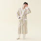 Man in an off-white fleece kimono style robe with olive green and red stripes, hand raised to his forehead