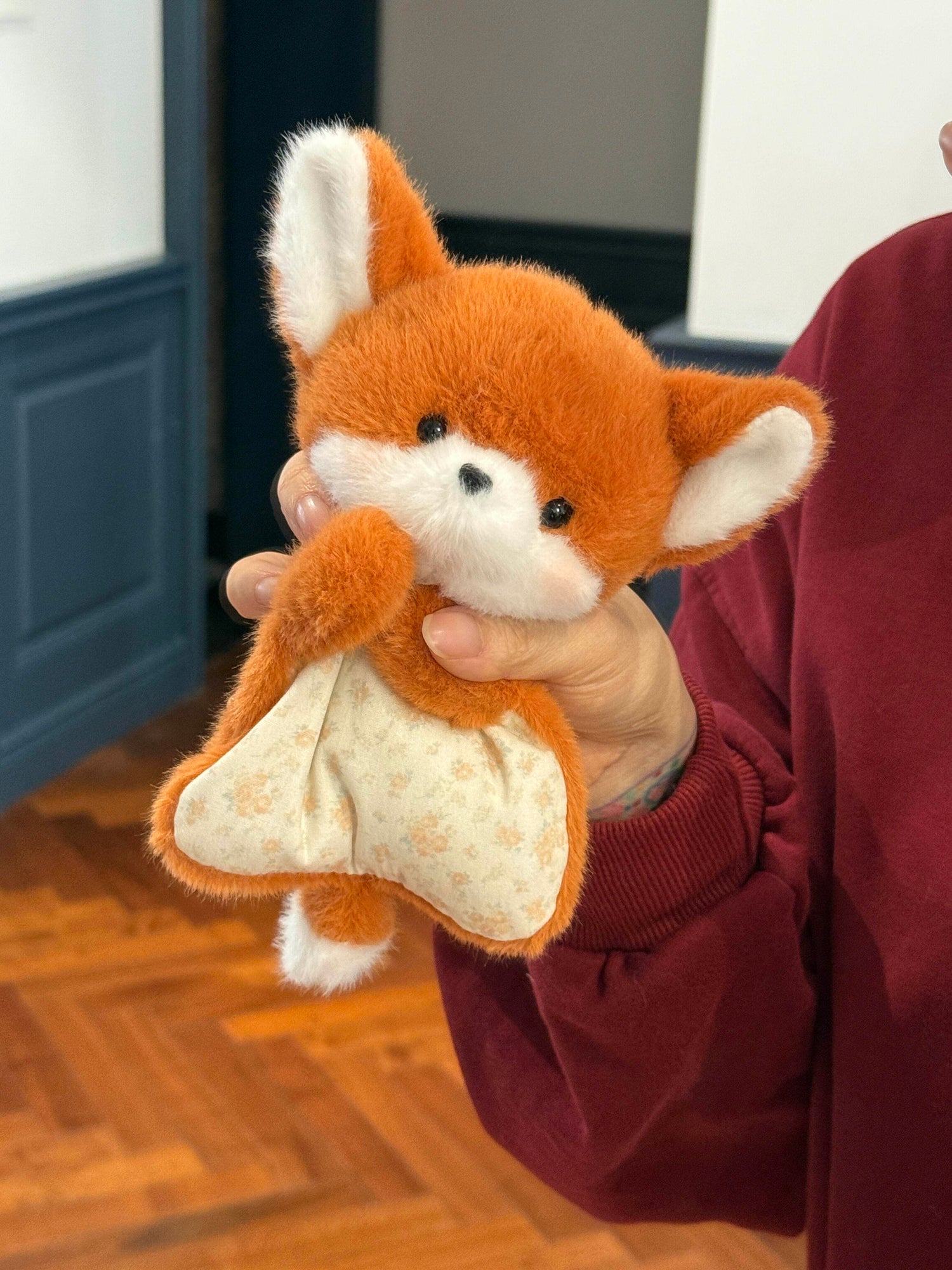 Squishy bean bag plush animal toy shown in hand, soft faux fur head and cotton apron body