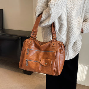Woman carrying a brown washed leather shoulder tote with front zip pockets
