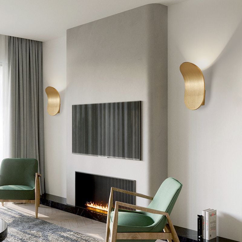Two brushed gold wall lamps on either side of a television above a fireplace in a living room
