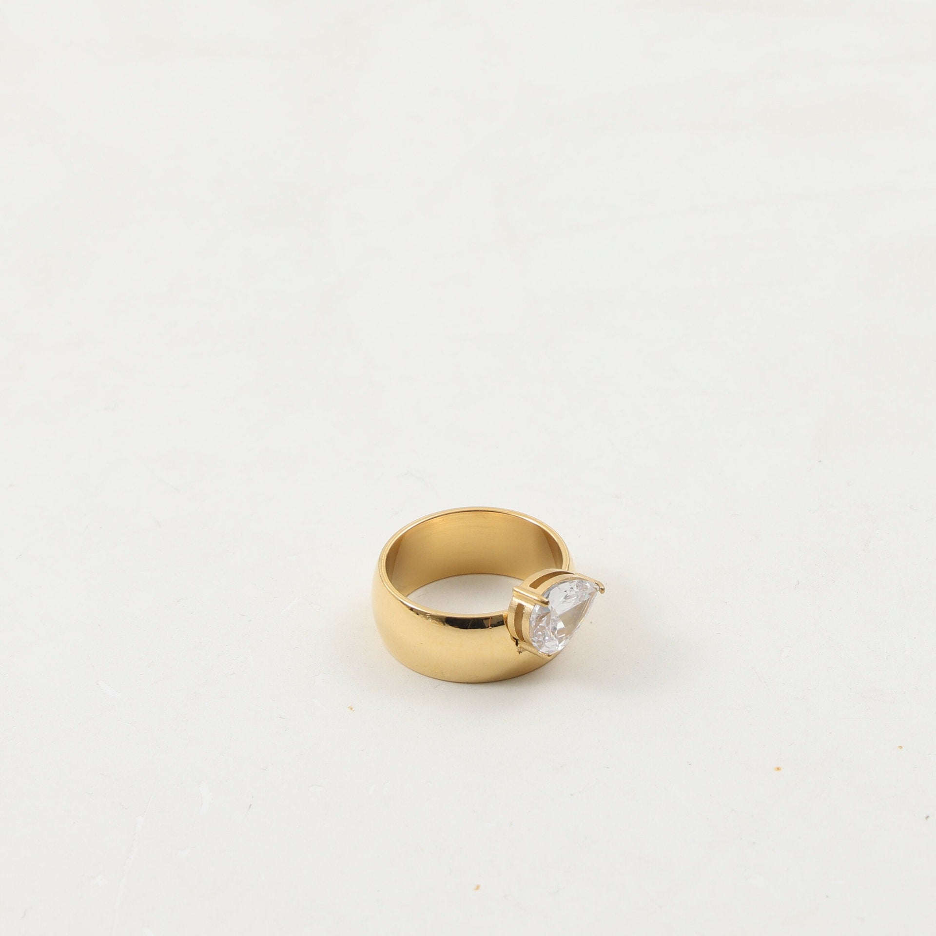 Gold-plated zircon drop ring styled on a hand in a softly lit interior scene