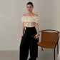Woman in black high waist wide leg pleated trousers and off shoulder top standing