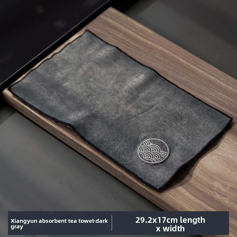 Dark gray tea cloth with a wave roundel motif on a walnut tray, labelled 29.2 by 17 cm