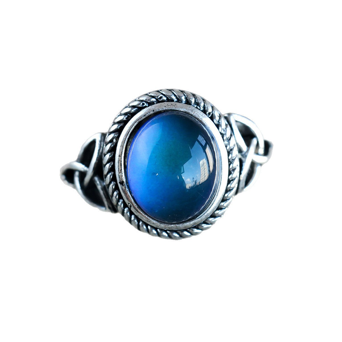 Silver tone Celtic knot mood ring with iridescent oval stone on a stone surface