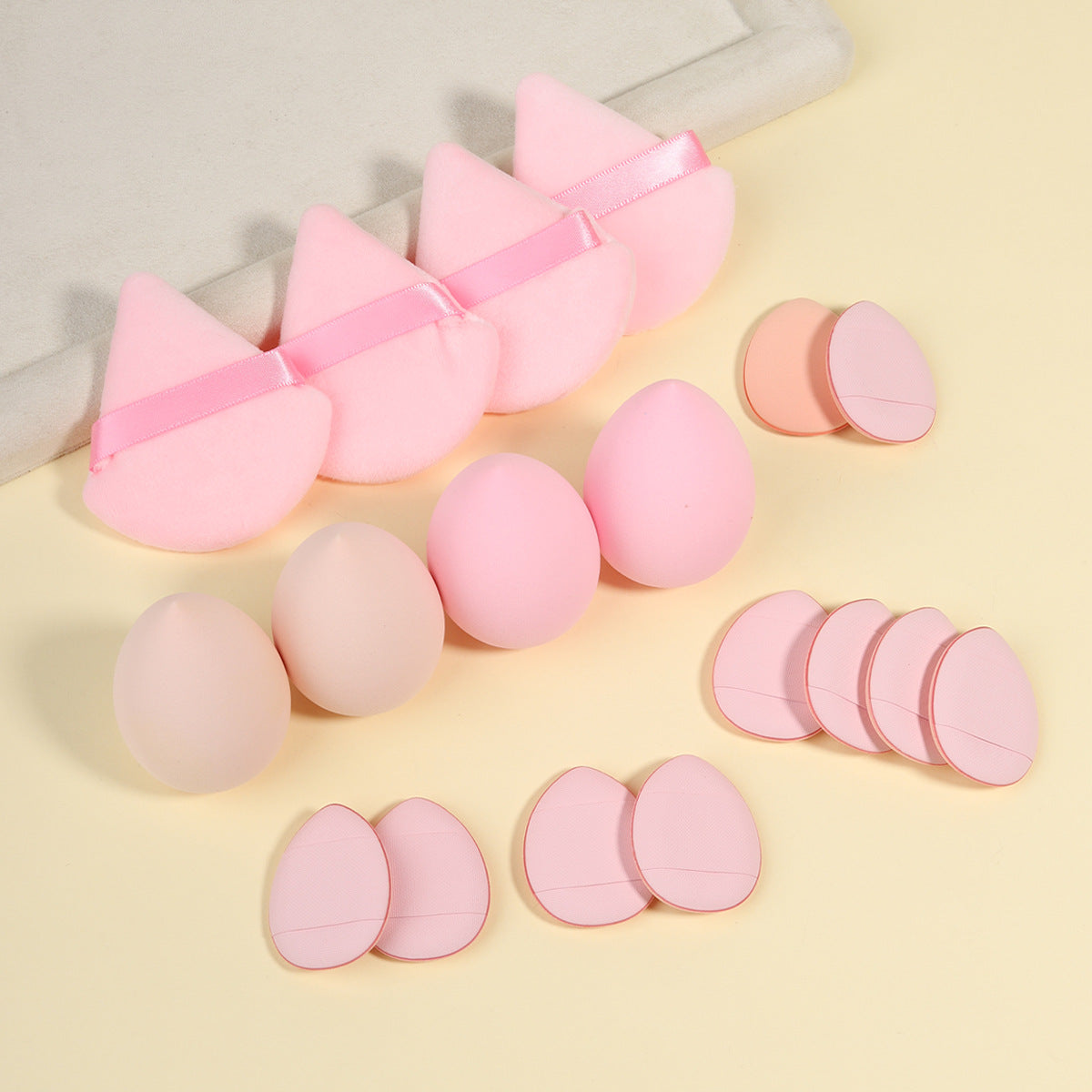 Row of foam makeup sponges and velvet powder puffs laid out by color