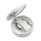 Open white compact holding a pair of magnetic false eyelashes and the clip