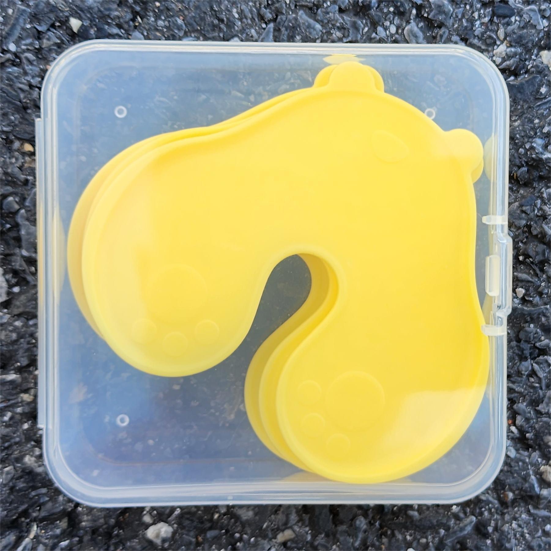 Stack of four yellow bear shaped skin pads inside a clear plastic storage box with a clip lid