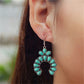 Close up of a woman's ear wearing a crescent drop earring with turquoise colored teardrop stones