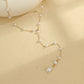 Close view of the Y junction where the pearl chain drops into one strand ending in a teardrop pearl