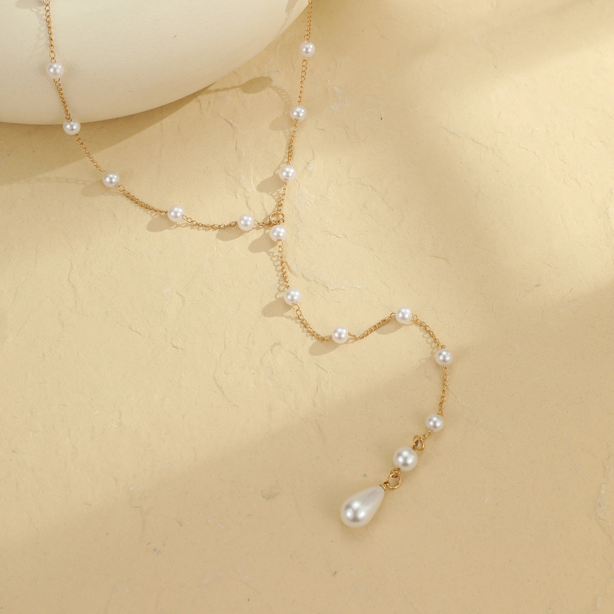 Close view of the Y junction where the pearl chain drops into one strand ending in a teardrop pearl