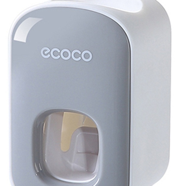 Grey wall mounted toothpaste dispenser front with a strip of paste in the dispensing window