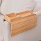 Natural bamboo armrest tray with a two-section top organizer on the arm of a cream sofa