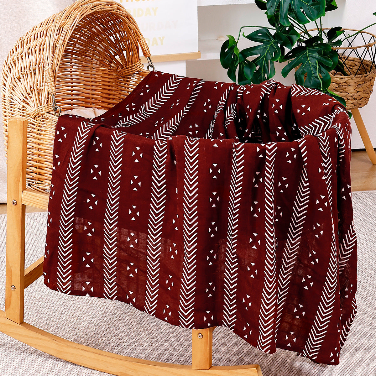 Large cotton muslin gauze baby blanket laid out, showing the loose breathable weave and print