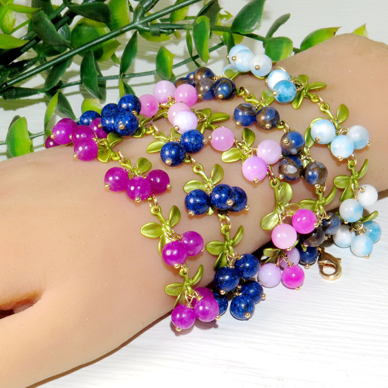 Close view of glossy round beads bunched like berries with matte green enamel leaves
