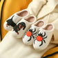 Cream plush slippers with tufted black dachshund and black spider designs on a cream coat