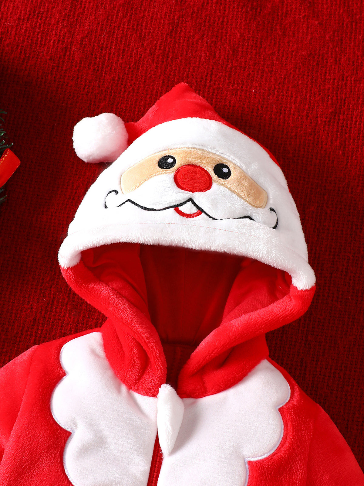 Close up of the stitched Santa face with red nose on the hood of the red fleece baby jumpsuit