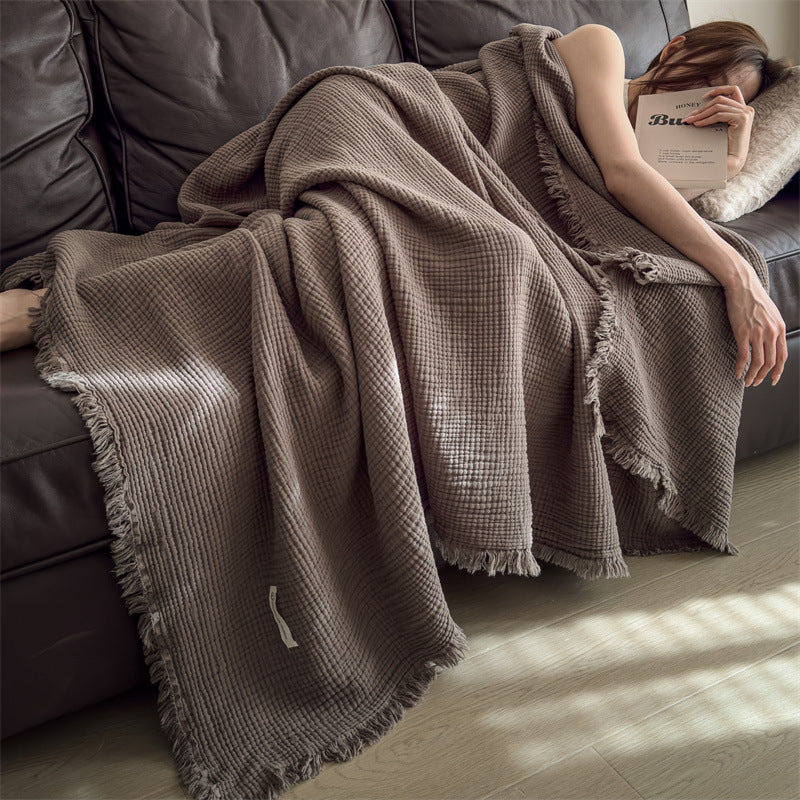Dark Chestnut Brown cotton gauze throw blanket with tassel fringe, draped over a woman asleep on a dark sofa, view 3 of 4