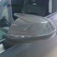 Close-up of the horn-style carbon fiber cover installed on a gray car door mirror beside the window