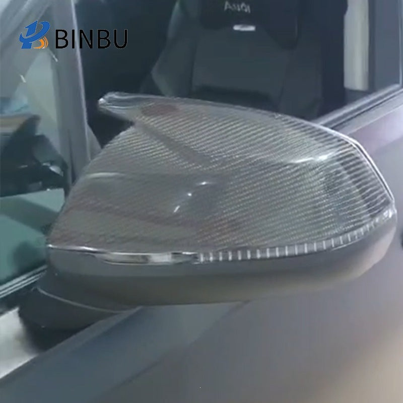 Close-up of the horn-style carbon fiber cover installed on a gray car door mirror beside the window
