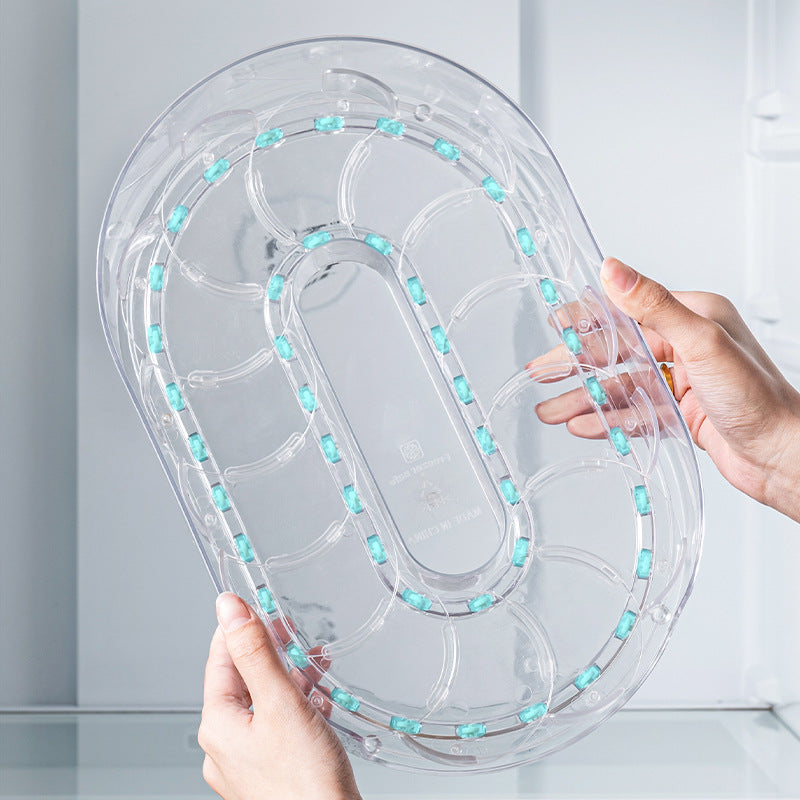 Hands holding the clear base of the rotating tray, showing an oval track with small teal rollers on the underside