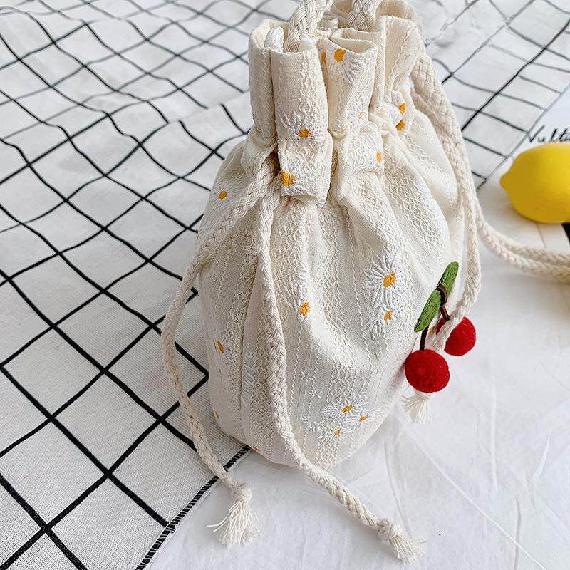 Side view of canvas bucket bag showing drawstring bow top and braided rope strap