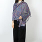 Woman wearing a blue and purple paisley shawl over her shoulders with navy tassels at the front