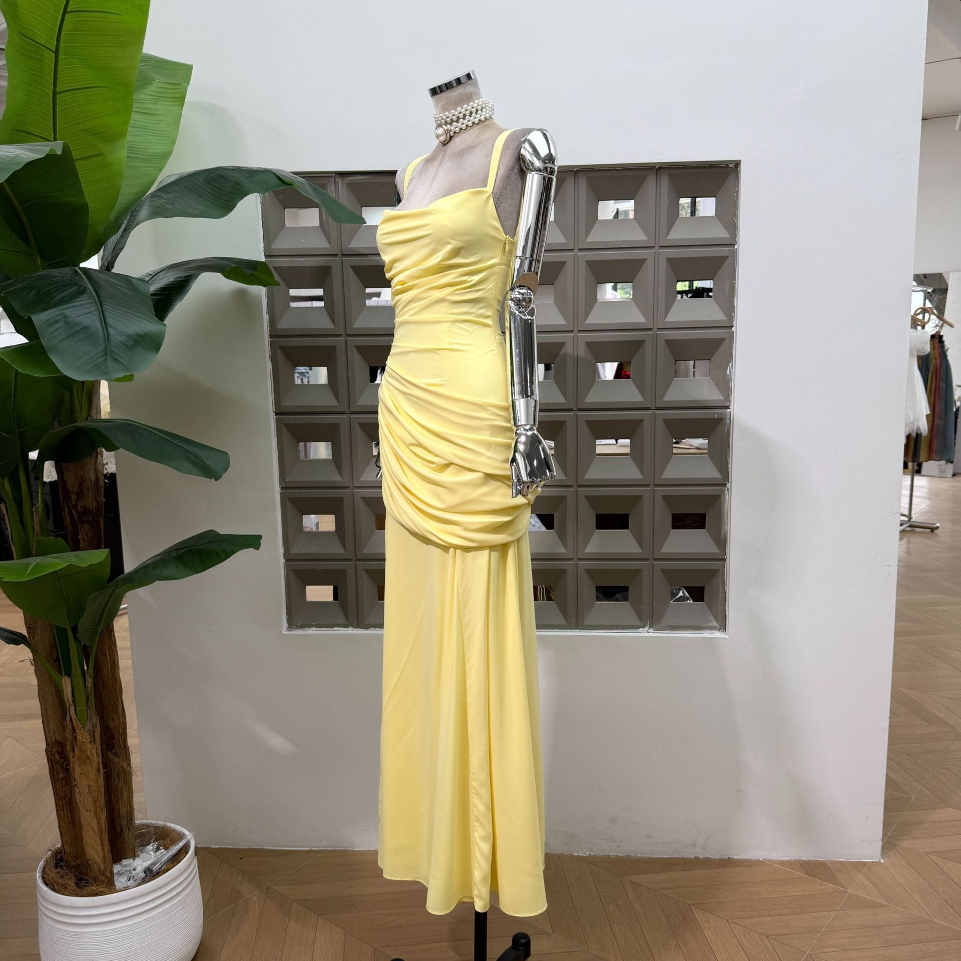 Butter yellow ruched maxi dress seen from the side on a dress form, draped hip panel